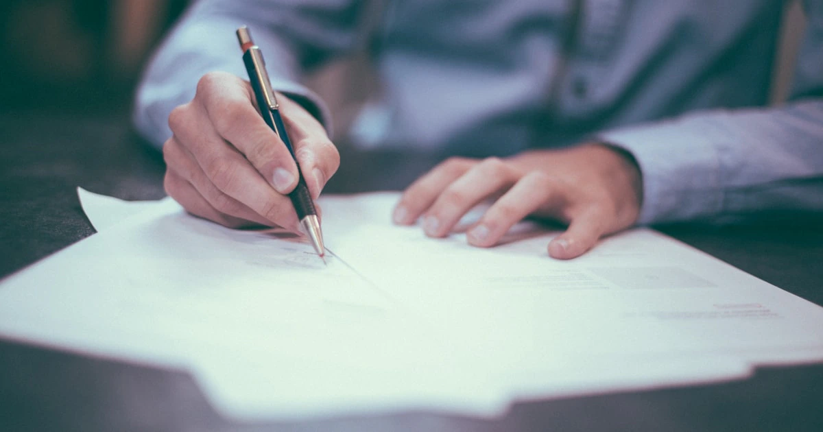 Business professional signing property contract documents at a desk