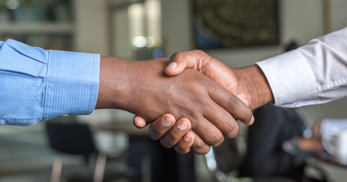 Business professionals shaking hands across a table during a meeting