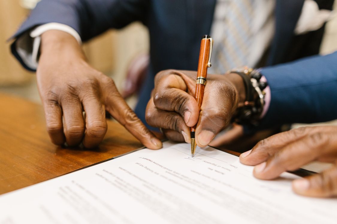Business professional signing a legal contract document with a pen