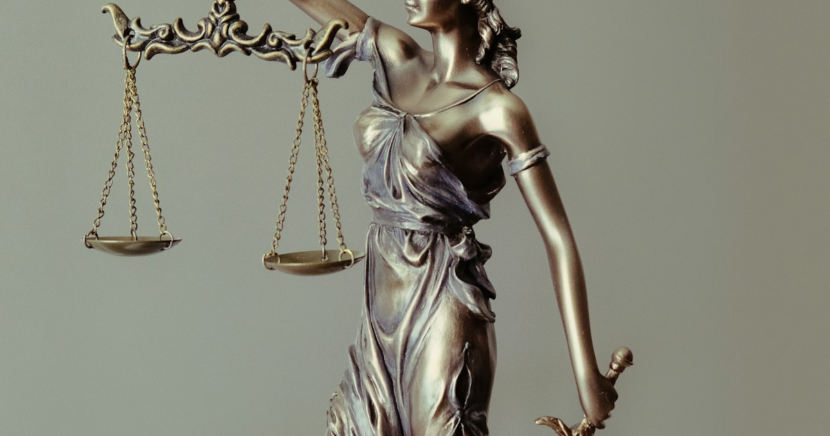 Golden scales of justice balanced against a dark background, representing fairness in legal proceedings