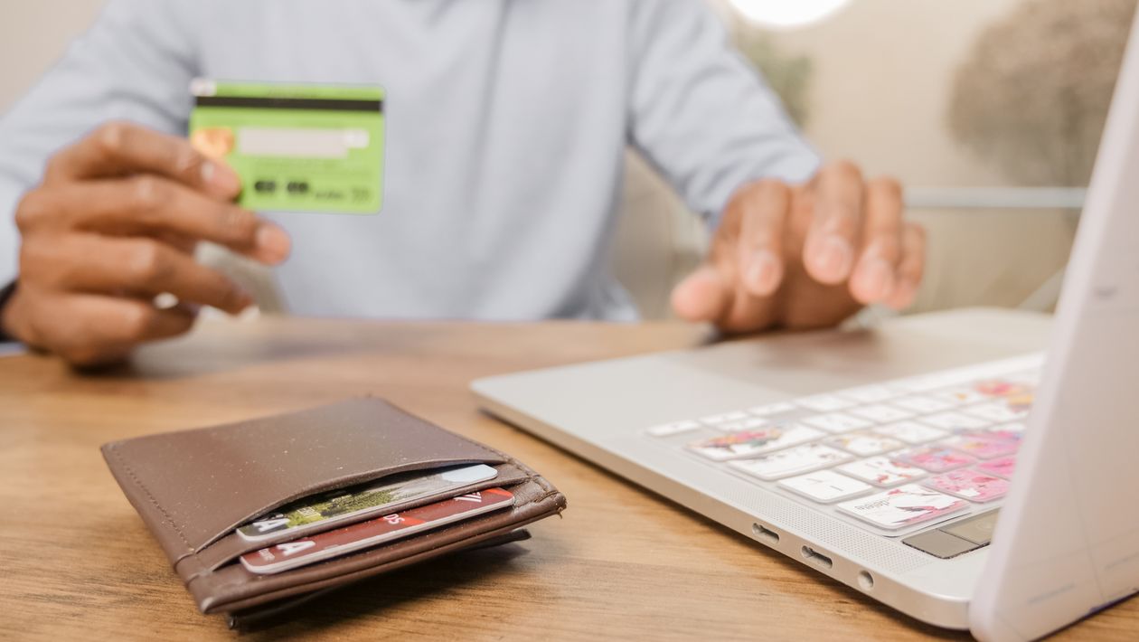 Person holding a bank card while shopping online on a laptop