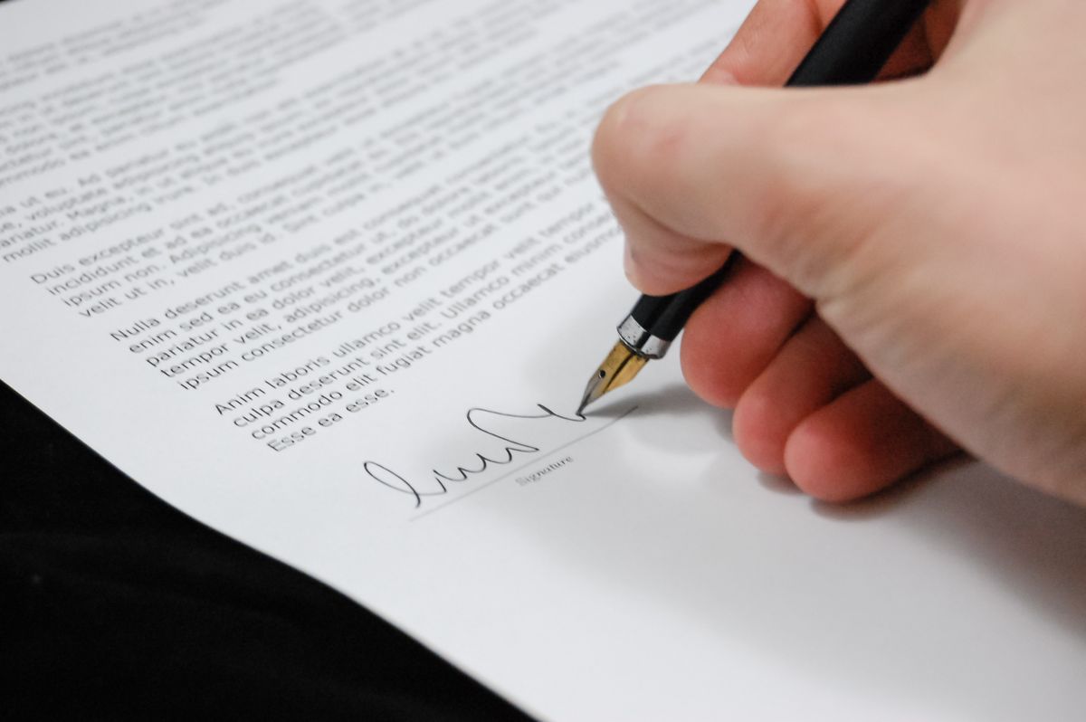 Hand signing a legal property document with a pen