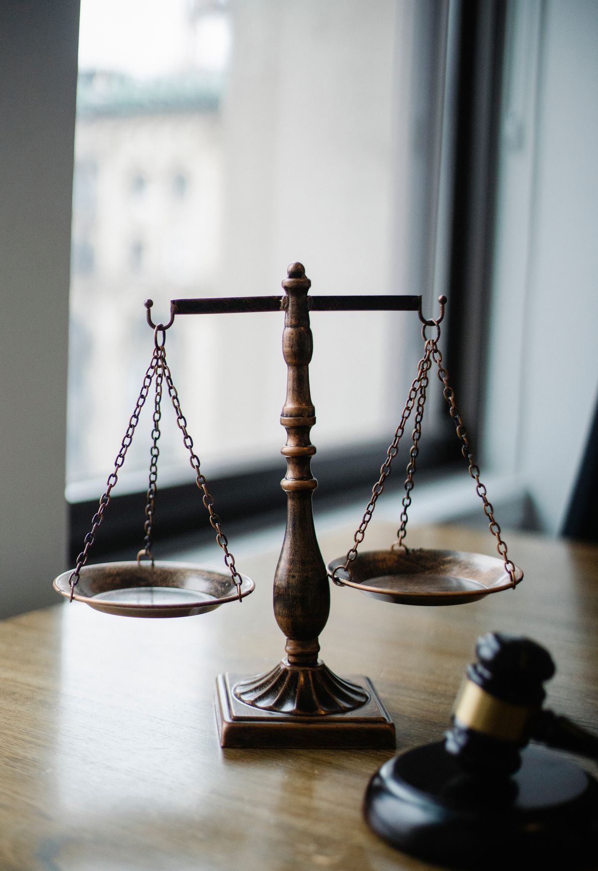Brass scales of justice and a wooden gavel on a desk, symbolizing legal dispute resolution