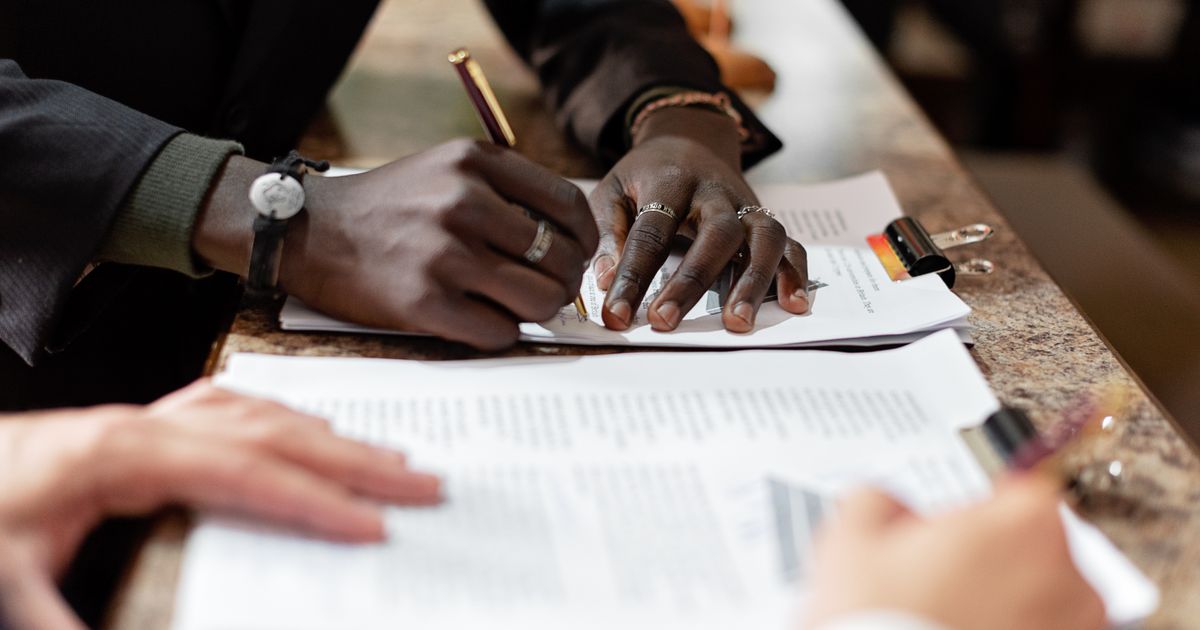 Business professionals signing legal documents at a conference table